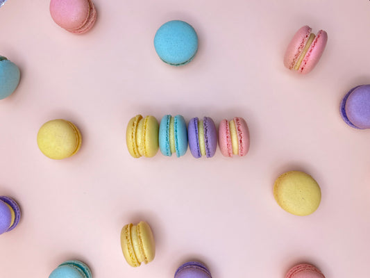 Colorful mini macarons arranged on a light pink background