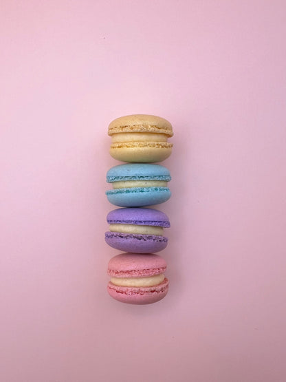 Assorted mini macarons lined up on a pink background